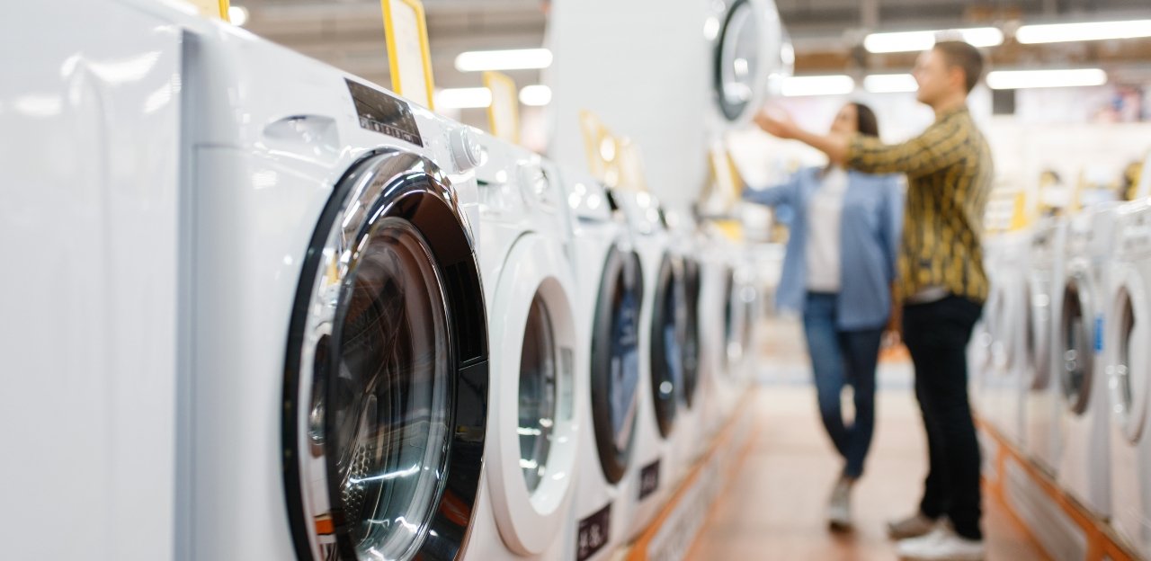 Couple comparing new washing machines in an appliance store showroom