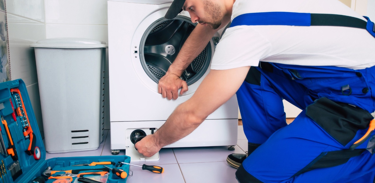 Appliance repair technician servicing a washing machine drain filter
